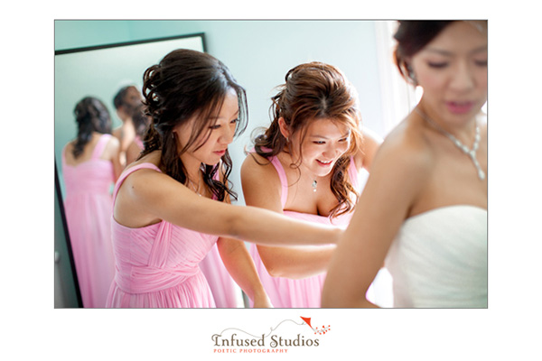 Bridesmaids helping bride into dress