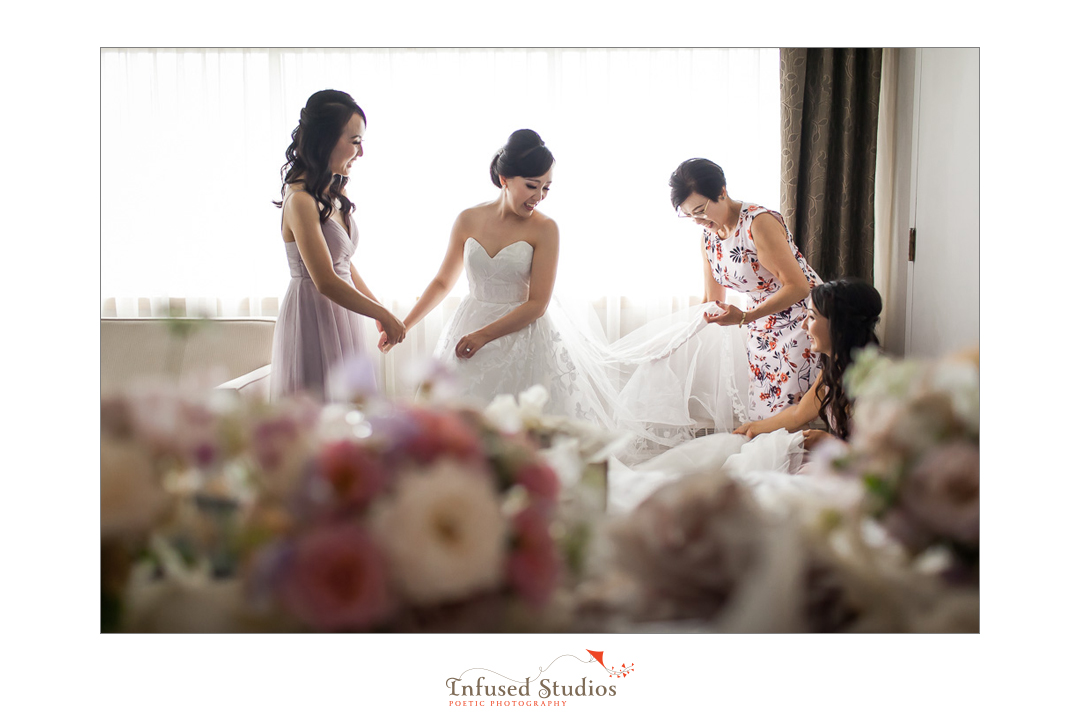 Bride getting into white dress by Calgary wedding photography by Infused Studios