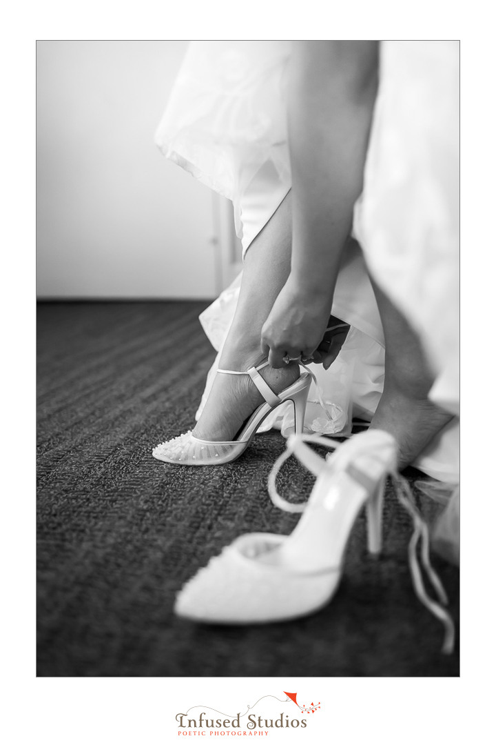Black & white artistic shot of bride putting shoes on by Calgary wedding photography by Infused Studios