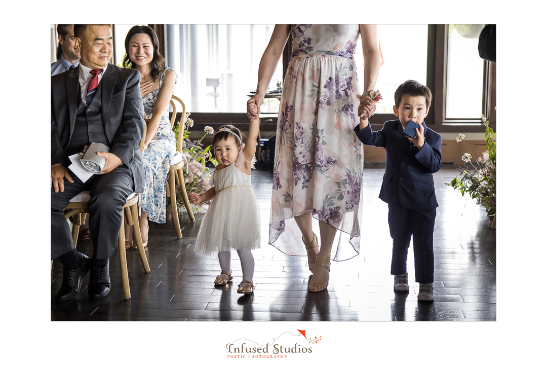 Pageboy & flower girl coming down aisle by Calgary wedding photographers Infused Studios