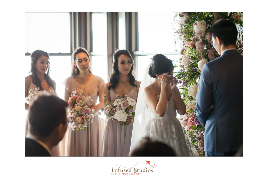 Bride wiping away tears during vows by Calgary wedding photographers Infused Studios